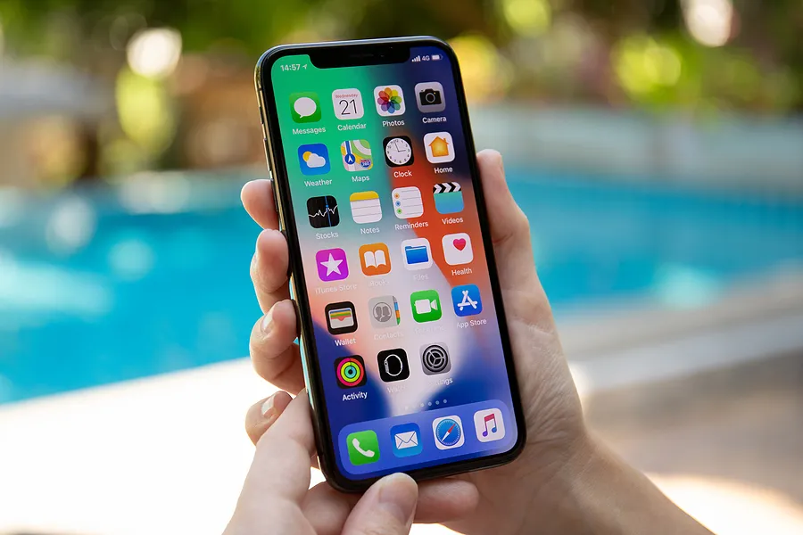 Una mano sosteniendo un iPhone al aire libre para mostrar en qué consiste la función True Tone del iPhone.