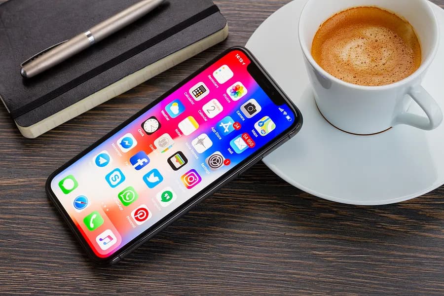 Un iPhone apoyado contra una taza de café