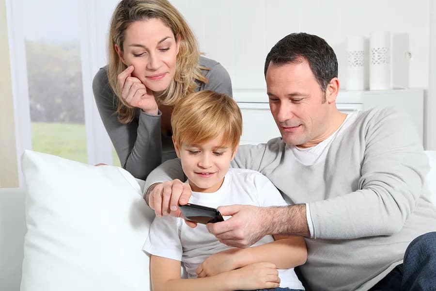 Una madre, un padre y un niño mirando un móvil.