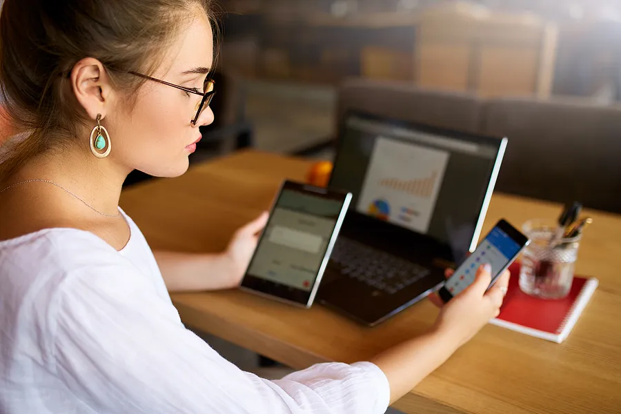 Mujer con un teléfono, una tableta y un ordenador portátil.