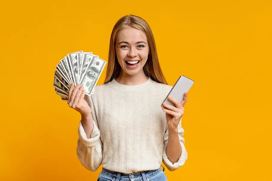 Mujer con un teléfono y dinero en la mano.