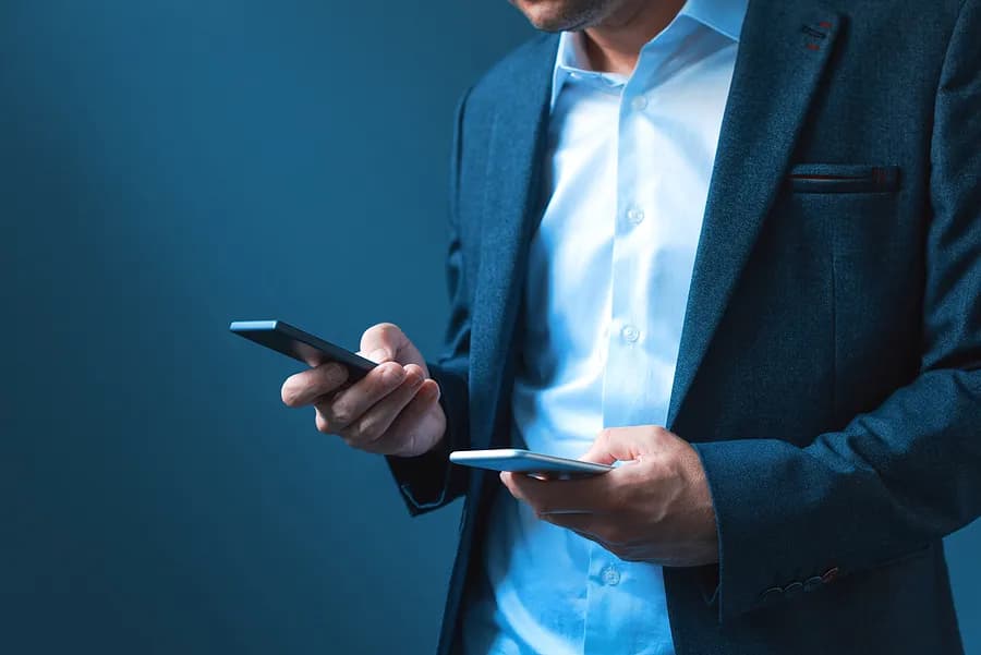 Un hombre con dos teléfonos en la mano.
