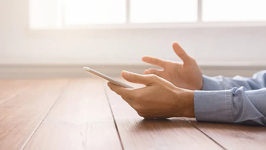 Persona con un iPhone cerca de una ventana, que ilustra cómo desbloquear el código de acceso del iPhone sin necesidad de un ordenador.