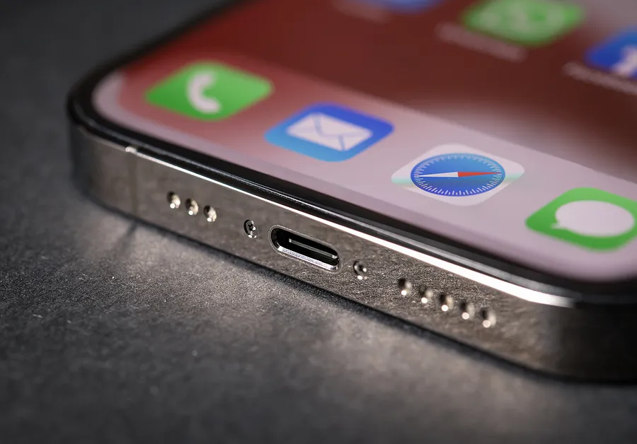 Primer plano del puerto de carga de un iPhone con iconos de aplicaciones visibles en la pantalla, que ilustran los problemas de carga del iPhone.